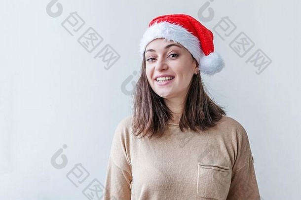 戴着红色圣诞老人帽子的美丽女孩，被隔离在白色背景上，看上去快乐而兴奋。年轻女子肖像，真实情感。圣诞快乐，新年快乐。