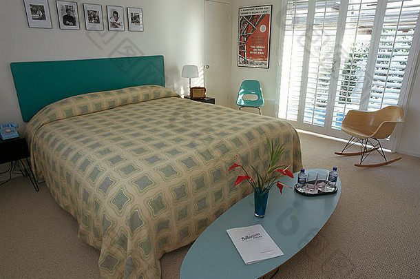 现代卧室中的椭圆形咖啡桌和Charles Eames椅子，床上有图案盖，床头有软垫