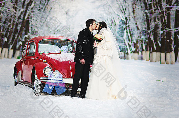 冬天的新婚夫妇在老式汽车旁