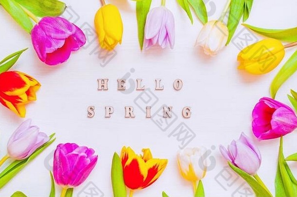 木制背景上有可爱的春天郁金香花，上面写着春天好，春天假期明信片。以郁金香花为背景的春花