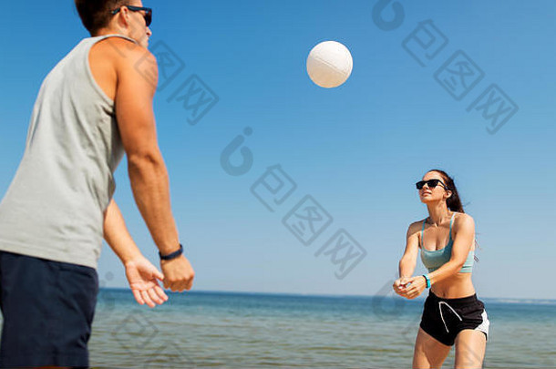 快乐的一对在夏日海滩上打排球