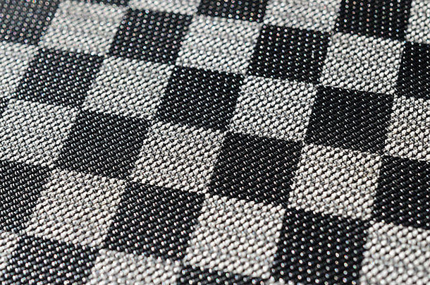塑料纹理以非常小的布装订的形式出现，用黑色和灰色绘制成棋盘的样式。微距镜头。