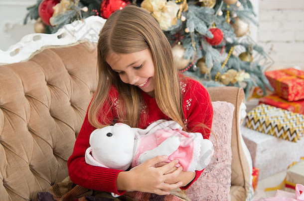 小女孩在圣诞树旁拥抱可爱的兔子。小女孩抱着兔子<strong>玩具</strong>。小孩玩软<strong>玩具</strong>。小孩带着礼物开心地笑着。最好的圣诞<strong>玩具</strong>。我爱我的兔子。