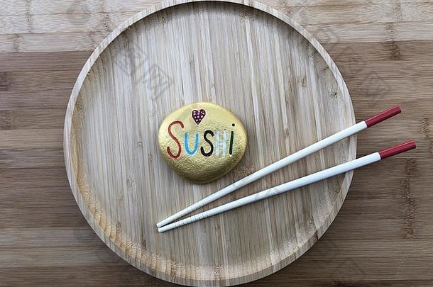 寿司的概念是在木制盘子里放一块彩石和两根中国棍子