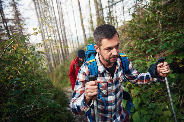 专注的徒步旅行者独自行走在陡峭的森林小道上