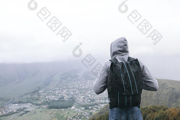 雾天，乔治亚州高加索山脉背景下背着背包的年轻游客