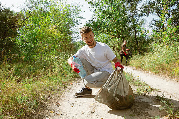 构建健康的首页集团志愿者整理垃圾海滩阳光明媚的一天年轻的男人。女人护理自然环境采取瓶包概念生态
