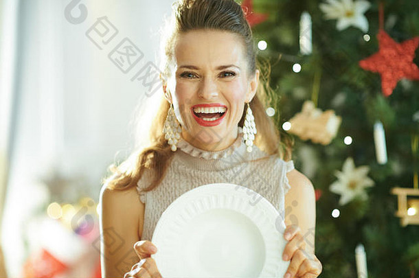 微笑年轻的家庭主妇圣诞节树持有服务白色晚餐<strong>板</strong>