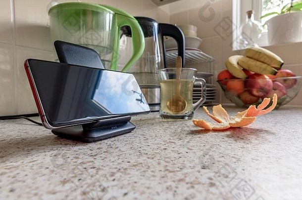 智能手机<strong>无线充电</strong>在厨房桌面上的<strong>充电</strong>座上。