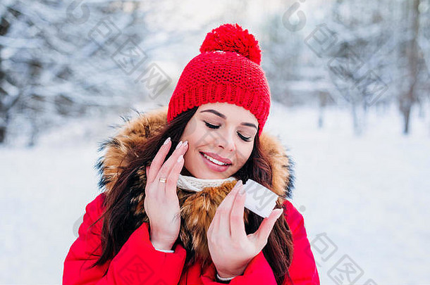 一位美丽女子的冬季肖像，在冬季背景上涂有面霜和雪花。冬季面部护肤