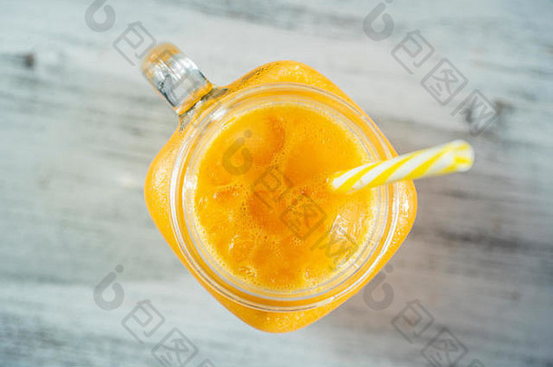 白色木桌上的玻璃杯子中的新鲜有机黄色思慕雪，特写。清爽夏日水果饮料。健康饮食的概念。海荞