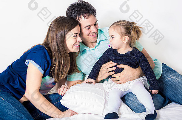 幸福的家庭，母亲，父亲和女儿在白色的床上
