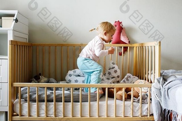 可爱的有趣的蹒跚学步的女孩玩婴儿床卧室