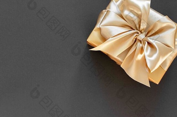 金色礼品的节日背景，黑色背景上金色丝带和蝴蝶结的盒子，平面布置，俯视图，空间
