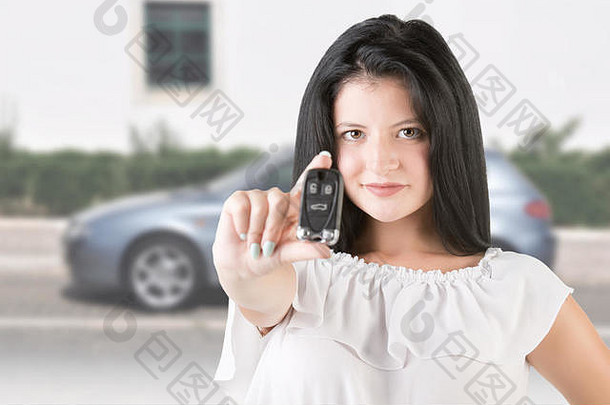 一名妇女拿着汽车钥匙，背景是一辆汽车