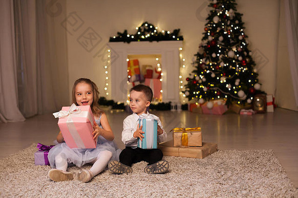 男孩女孩开放圣诞节礼物圣诞节树一年的夏娃家庭庆祝活动