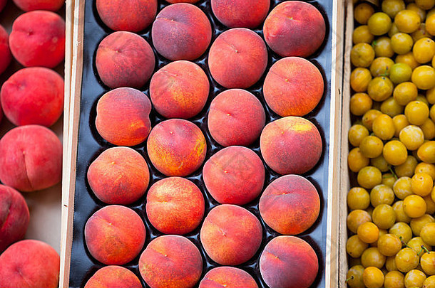 市场上出售的新鲜桃子和李子。有选择焦点的水平镜头