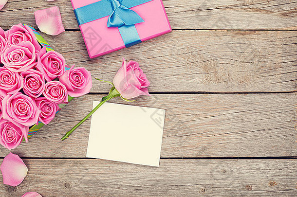 情人节贺卡或相框和礼品盒，木质桌上放满粉红色玫瑰。俯视图