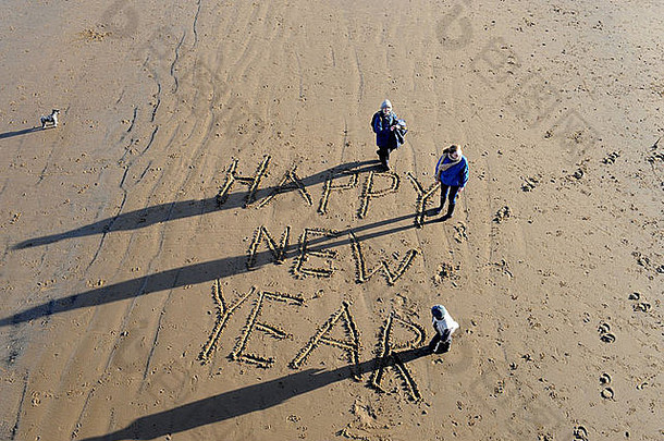 英国克利夫兰索尔特伯恩海滩，祖母和孙子孙女们在沙滩上写下新年快乐的祝福语