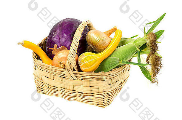 白色背景上的一个大柳条筐，装满了新鲜采摘的各式花园蔬菜。