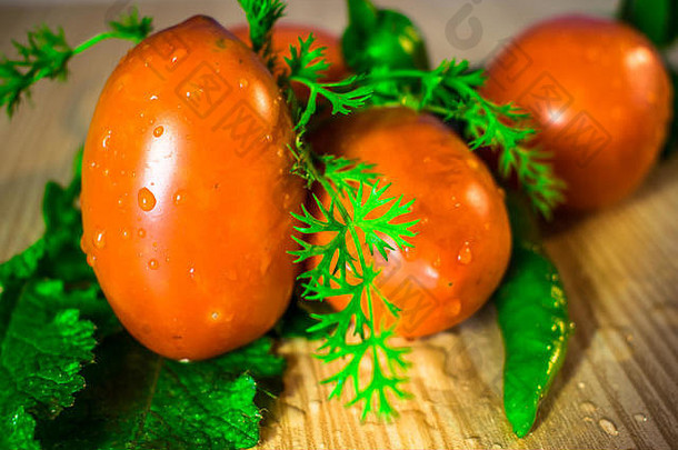 新鲜的健康的红色的西红柿绿色热辣椒香菜叶子水滴木表格