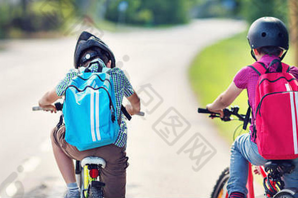 带着背包的孩子们在学校附近的公园里骑<strong>自行车</strong>