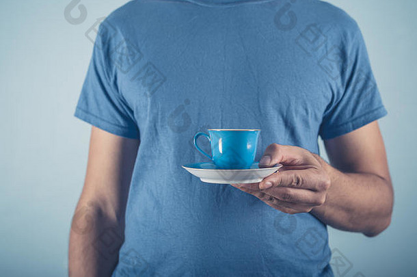 一个穿着蓝色t恤的年轻人拿着一杯浓咖啡