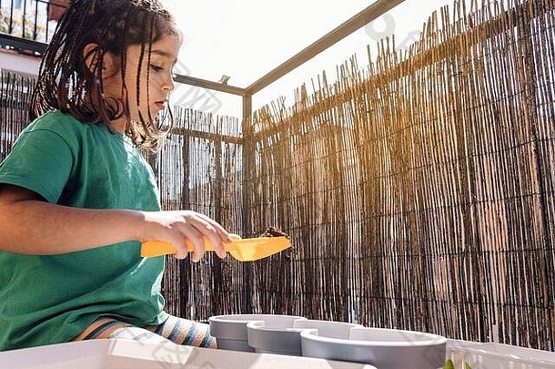 孩子用铁锹把泥土放在阳台盆里种植，爱好在家，可持续生态的生活方式理念