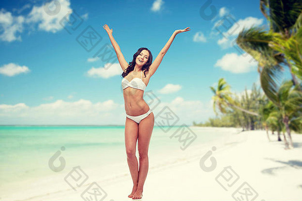 穿着比基尼泳衣在海滩上跳舞的快乐女人