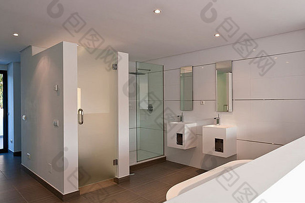 在西班牙南部新建别墅的现代白色浴室中，方形梳妆台上有两个淋浴和洗脸盆