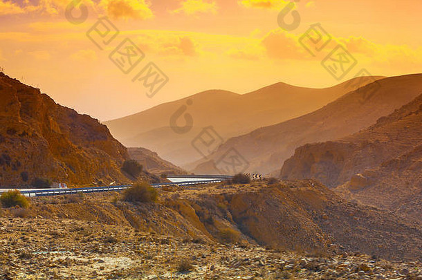 沙漠中的日落。沙漠中的山路。从道路附近的停车场可以看到砂岩山脉。从阿拉德到死海的道路。