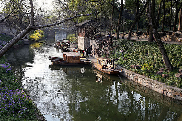这是一张中国一座城市沿河几栋老房子的照片。墙壁是白色的，但又脏又灰。水是绿色的。弗洛