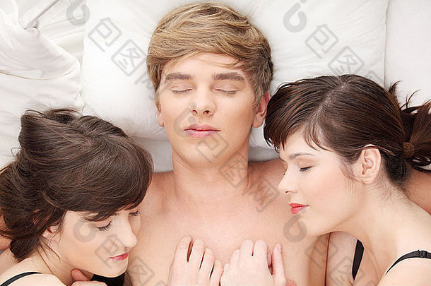 年轻英俊的男子和两个女孩躺在床上