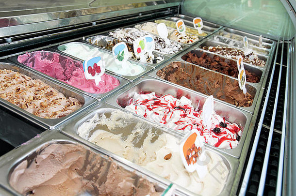 带有奶油和水果的冰淇淋冰箱意大利冰淇淋钢制柜台，具有许多清新的甜的可舀口味。冰淇淋展示。