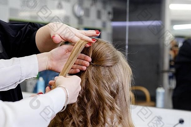 美发师发型师发型培训中心的发型。美发师在美容院为长发金发女人做发型。教师