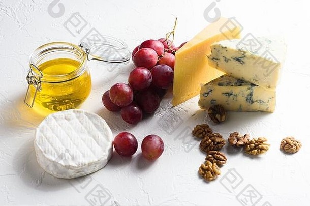 白底沙司、葡萄、坚果、意大利和法国奶酪以及蜂蜜和葡萄酒水果拼盘。侧视图。