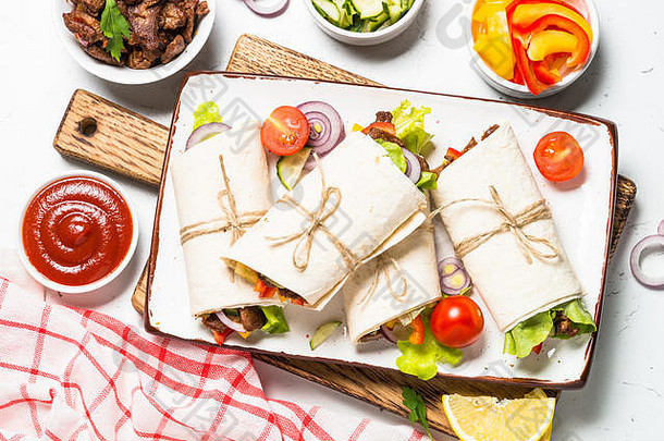 墨西哥<strong>玉米饼</strong>裹着牛肉和蔬菜放在白色的木桌上。传统的拉丁美洲食物。顶视图。