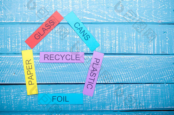 在蓝色风化背景上展示罐、纸、箔、塑料、玻璃和回收的回收概念