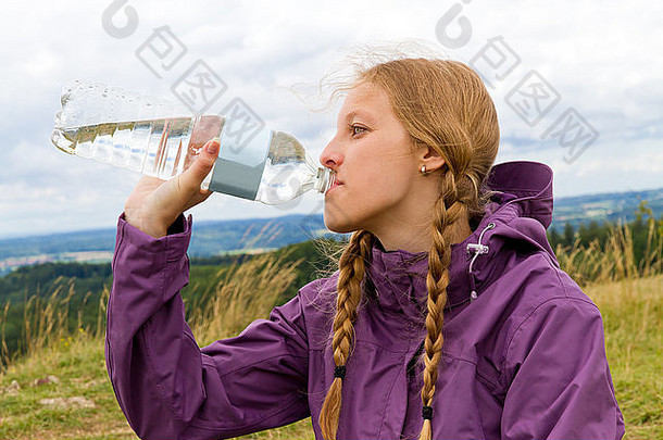 肖像年轻的金发碧眼的女人户外喝水