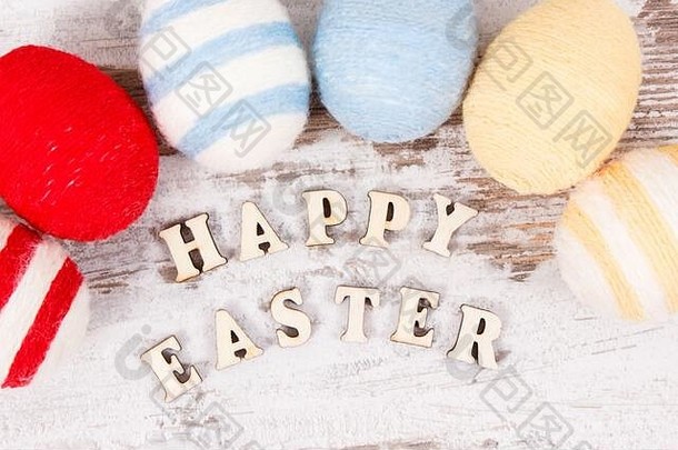 在古老的乡村木板上题词“复活节快乐”和“彩蛋包裹羊毛线”，体现节日装饰理念