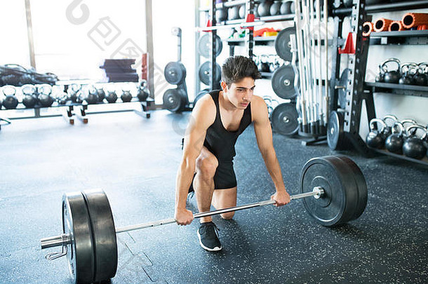 年轻健康的西班牙裔男子在健身房举重杠铃