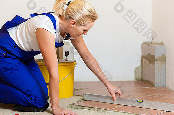 女建筑工人正在家里铺瓷砖；她大概是一个自己动手的人