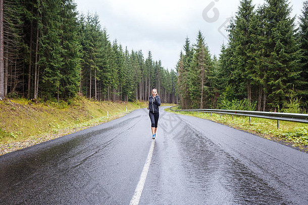 在多雨的山坡上慢跑的年轻女<strong>运动</strong>员