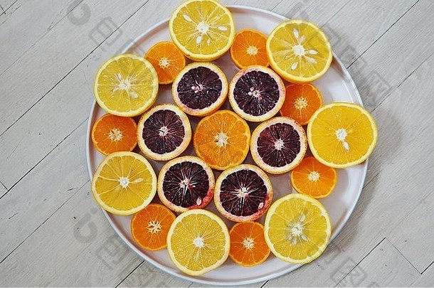 红宝石红的血橙、脐橙和克莱门汀在白色盘子上切成两半