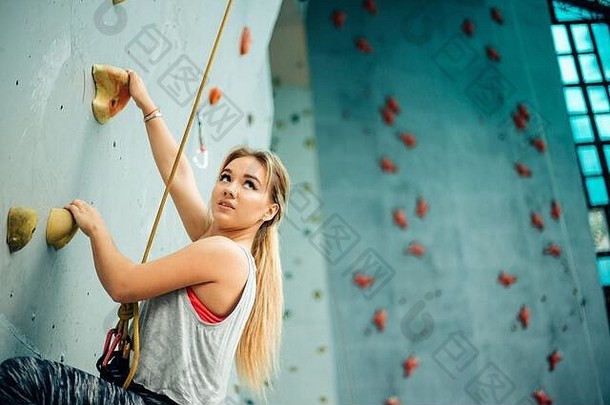 在人造墙体育馆接受训练的迷人的年轻职业攀岩运动员