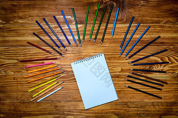 木桌上放着<strong>彩色</strong>铅笔的空笔记本