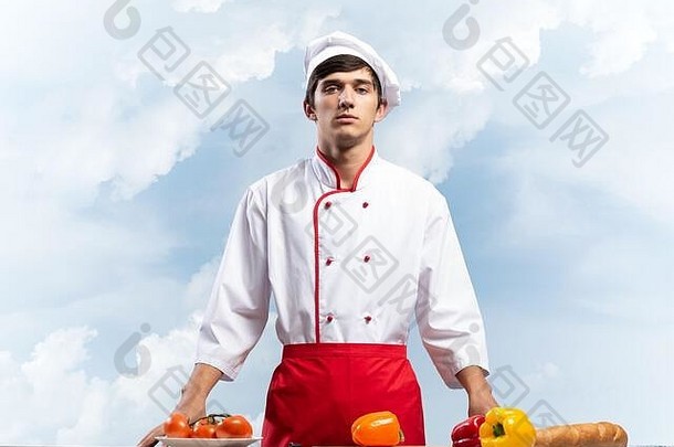 年轻的男厨师站在餐桌旁