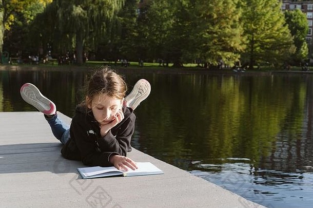 这个女孩在池塘边读书。放松与自我教育理念