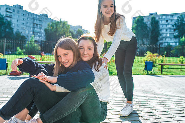 三个十几岁的女孩在城里玩滑板，在夏天，在放学和<strong>大</strong>学<strong>放假</strong>后休息。秋天街头的休闲保暖服