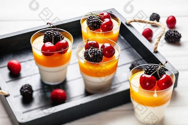4杯芒果盘，装在木制托盘上，上面放着黑莓和樱桃